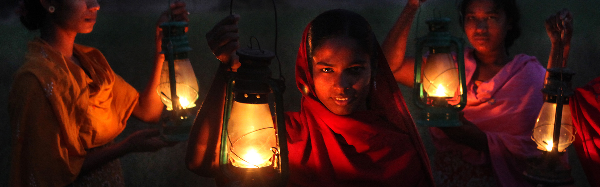 Girls holding glowing lamps in the dark.